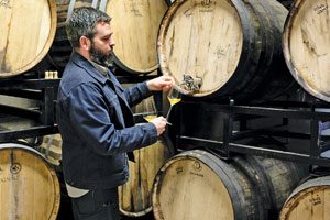 Ryan Burke pouring glass of cider from barrel, at Angry Orchard.