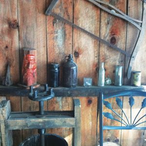 photo of the wood paneled wall, and shelf with vintage items, and small fruit press, at Bashakill Vineyards.