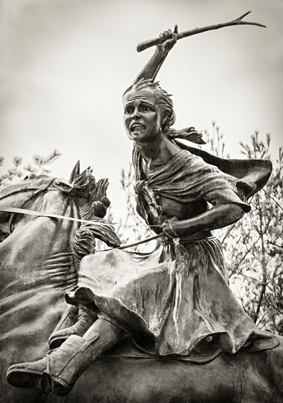 large statue of girl riding horse with hand raised