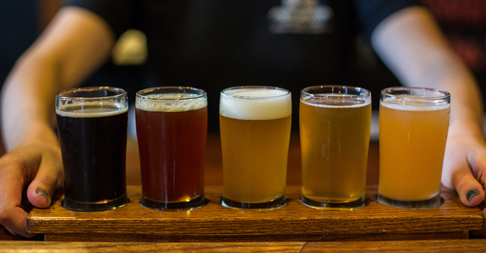 flight of five beers on wood tray