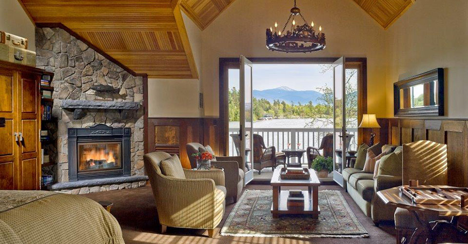 interior of lodge with stone fireplace and open glass door with view of lake and mountains