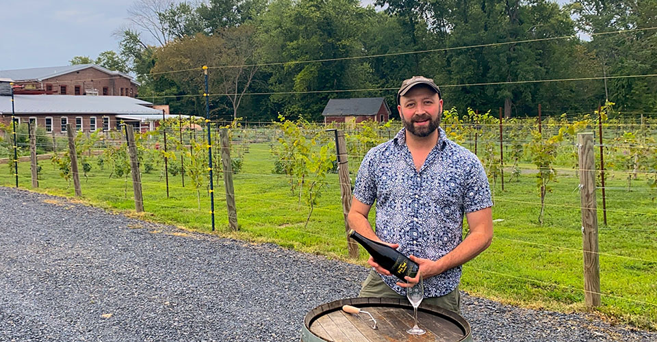 vineyard view with man in front of barrel holding wine in foreground