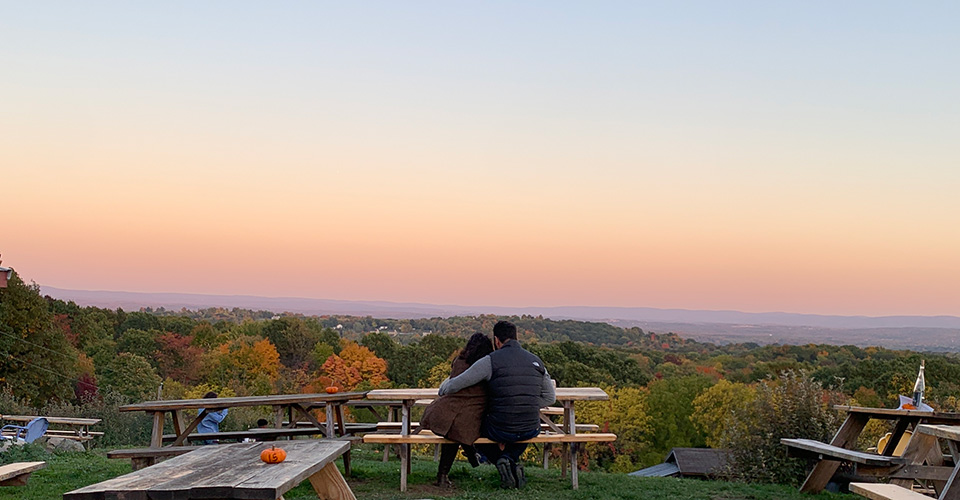 couple sitting at picnic table at sunset with view of mountains in distance