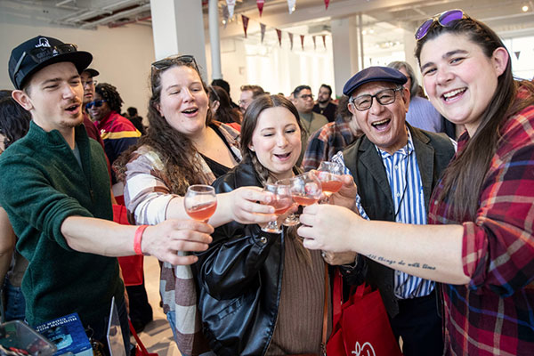 group of people at a festival cheering with cider glasses