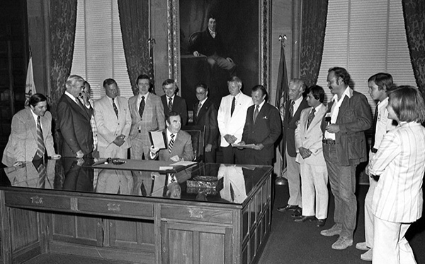 Governor High Carey signing Farm Winery Act with onlookers
