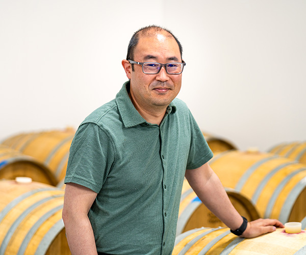 Director of Winemaking at Rolling Hills Estet Winery standing in from of wine barrels